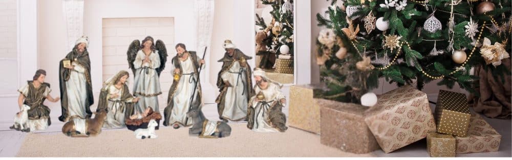 Elegant indoor Christmas scene featuring a complete Nativity set arranged by a fireplace, with a decorated Christmas tree and wrapped gifts nearby.